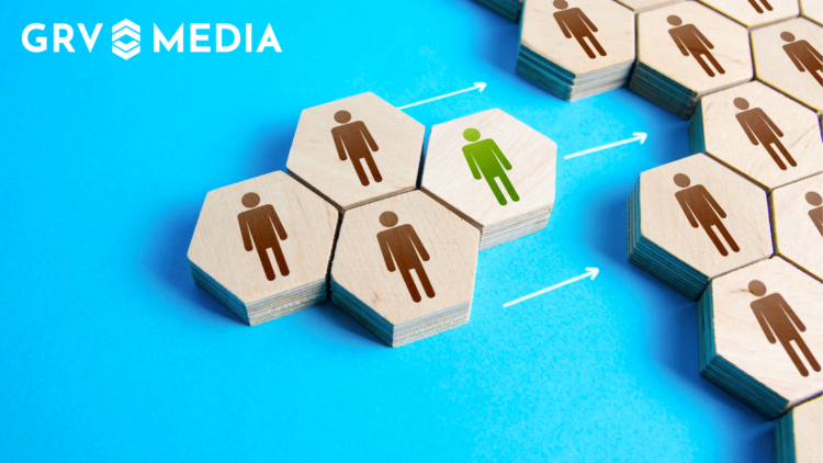 An image showing the integration of new hires into a larger team, depicted via wooden blocks with people on them.